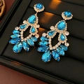 Gros plan de boucles d'oreilles dorées avec cristaux bleus sur un plateau à bijoux - Bleu