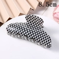 Detail view of 8.5cm checkerboard hair claw clip on a stylish display stand - 8.5cm / Black & White Checkerboard