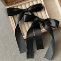 Detailweergave van twee zwarte satijnen strik-haarclips op een houten sieradendoosje - Eén paar / Zwart 1 Paar