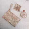 Macro shot of pink and gold floral jacquard phone bag with texture and wristlet detail - Pink