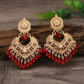 Golden bohemian hollow heart earrings with red bead tassels on dark wood background - Red
