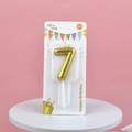 Golden number 7 gradient birthday candle on a white pedestal for party celebrations - Number 7 / Gold