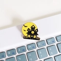 Detail of a yellow moon enamel brooch with bat and haunted house on a laptop keyboard - Full Moon Haunted House