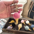 Close-up of a pink plush ice cream cone keychain with a gold ring and mini tassel detail - Rose Red