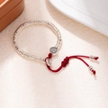 Macro detail of silver beads and red woven cord with a lucky Fú character charm - L312-2 Zaki Lhamo (Fortune)