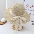 Detail of woven straw sun hat featuring elegant white lace ribbon and wavy brim design - One Size / Beige