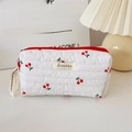 Close-up of white quilted cherry print makeup bag with red zipper and branding - Pencil Case