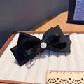 Detalle de pinza para el pelo con lazo de satén negro y perla en bandeja de terciopelo - Pinza de Banano con Lazo Negro
