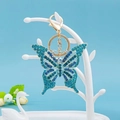 Dettaglio del portachiavi a fiocco con cristalli blu su supporto bianco elegante - Farfalla 26
