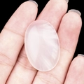 Oval pink rose quartz stone held in hand showing natural crystal texture and size - Agate