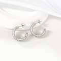 Elegantes pendientes de aro en C plateados con perlas sobre fondo blanco minimalista - Color Acero
