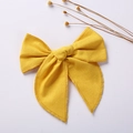 Close-up of yellow cotton linen bow hair clip with detailed fabric texture and stitching - Ginger Yellow