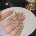 Elegant gold flower earrings with white zircon pavé held by hand for scale - Gold Flower Zirconia