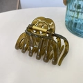 Close-up of a translucent brown pumpkin hair claw clip with golden metal spring on a white desk - Jelly Yellow Green