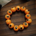 Macro shot of Halloween bracelet featuring orange beads with black spider web patterns - Spider Web