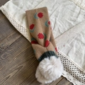Detailed view of brown knitted scarf featuring red floral patterns and white faux fur pompom - Khaki