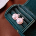 Primer plano de aretes de perlas rosas en terciopelo verde con cierres de silicona - Pin de Plata S925 / Perla Rosa 14mm