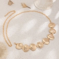 Detailed close-up of golden seashell-shaped body chain on a sandy beach setting - Beach Scallop Style (1699) / Gold