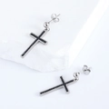 Close-up of silver cross dangle earrings with black inlay on a textured stone - Silver Tone (Black Zirconia)