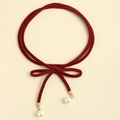 Détail d'un choker en velours bordeaux avec nœud délicat et pendentifs perles - Bordeaux