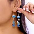 Boucles d'oreilles marines avec étoile de mer bleue et coquillage doré sur modèle - Style bleu océan
