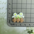 Close-up of small resin white flower on a brown fence measured with a ruler - White Flower Fence