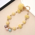 Close-up of a yellow plush ball keychain with resin rose beads and metal ring - Yellow