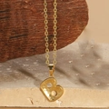 Macro shot of gold-plated necklace featuring a textured letter B pendant on stone base - Letter B