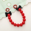Detail of red acrylic beaded phone strap featuring a black 3D bow and red round hook - Red
