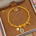 Primer plano detallado de una pulsera de cuentas en oro de 24k con trébol y gema púrpura - Dorado