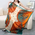 Green and orange autumn leaf print satin square scarf worn by a model in a cozy setting - Leaves and Baby's Breath