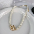 Elegant pearl necklace featuring a golden saturn pendant on a white ceramic plate - Golden Saturn Pendant Artificial Pearl Necklace (L0058XA)