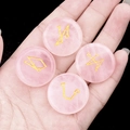 Hand holding four round rose quartz stones with engraved golden celestial symbols - Set of 4 / Rose Quartz
