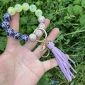 Detailed shot of leopard print beads and purple tassel on a wristlet keychain with gold ring - Purple Leopard