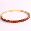 Close-up of 18K gold plated bangle featuring precision-cut red square zircon stones - Red Zirconia