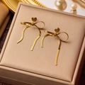 Elegant gold bow earrings with long snake chain tassels on a soft beige velvet box - Gold Earrings