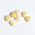 Polished yellow heart-shaped crystal ornaments scattered on a clean white background - Topaz