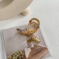 Detail view of colorful marble pattern hair claw clip with twisted metal structure - Orange Blue - Gold Clip