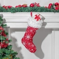 Red Christmas stocking with white plush cuff and embroidered snowflake hanging on fireplace - Red