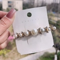 Elegant gold hair clip with pearls and rhinestones shown on a display card outdoors - Pearl Bobby Pin
