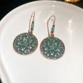 Macro detail of Bohemian hollow flower earrings with vintage turquoise finish in ceramic tray - Green Circular Ear Hook