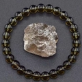 Detail eines dunkelbraunen Kristallperlenarmbands mit Naturstein auf grau strukturierter Fläche - Dunkelbrauner Kristall