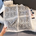 Detail view of a square leopard print silk scarf on a luxury plush background - Beige Leopard