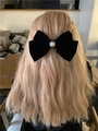 Fiocco per capelli in velluto nero con perla mostrato su capelli biondi mossi - Piccolo fiocco di perle