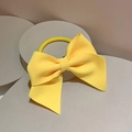 Detail of a bright yellow bow hair tie with textured fabric on a geometric display - Hair Tie / Yellow