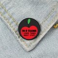 Black round teacher badge with red apple icon pinned on light blue denim fabric - I'm a Teacher Style (XZ62)