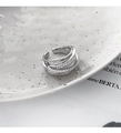 Détail d'une bague croisée argentée avec zircons pavés sur une assiette en céramique - Argenté