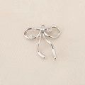 Close-up of silver bow pendant with zircons on textured fabric background - PJ0195-Silver Zirconia Bowknot