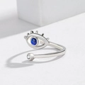 Macro shot of silver evil eye open ring with blue stone and fine metal eyelash details - Adjustable Open / White Gold