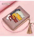 Close-up of pink leather wallet featuring cartoon cat patches and a tassel keychain - Purple